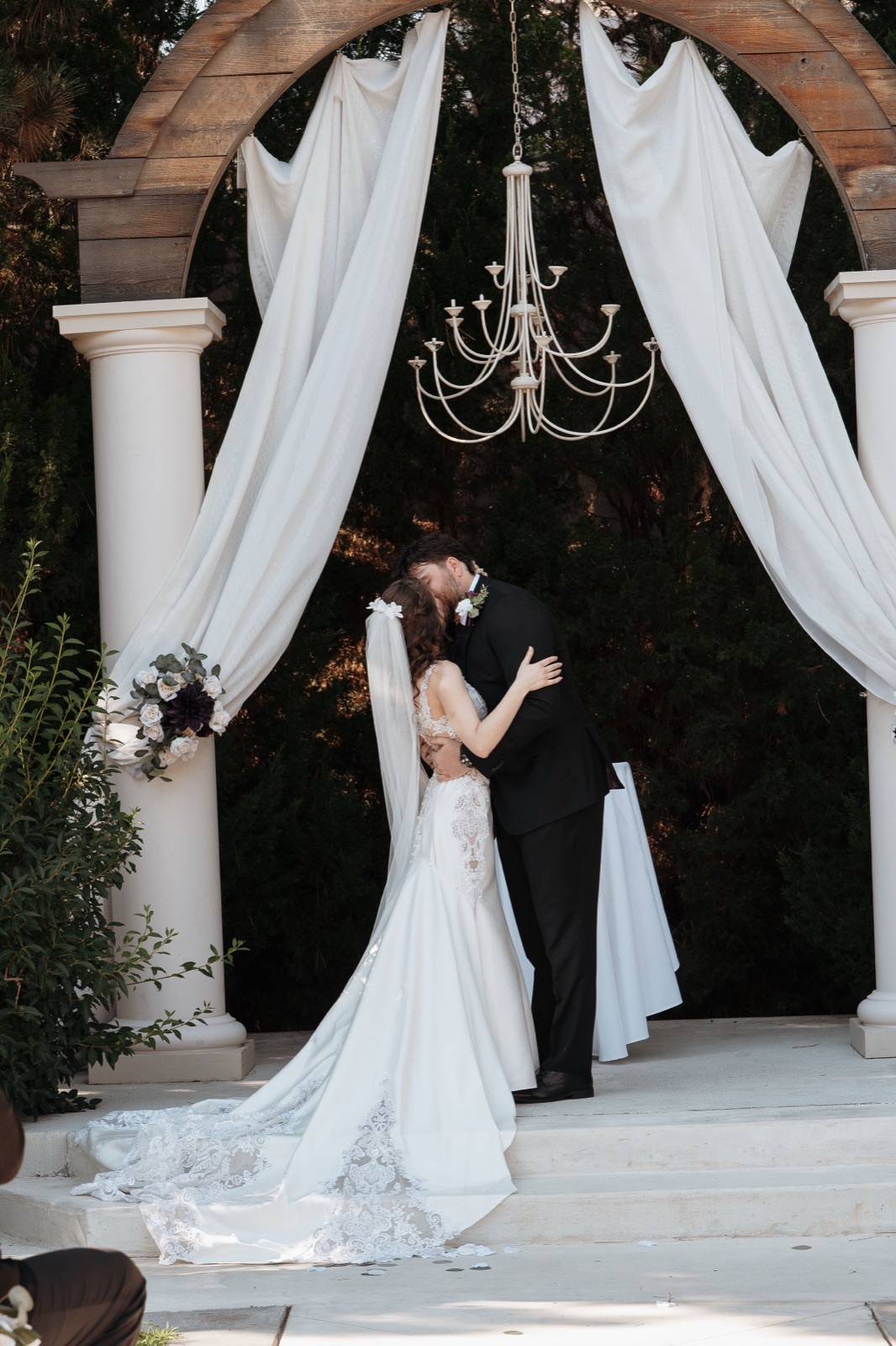 Bride and groom under arch with custom veil
